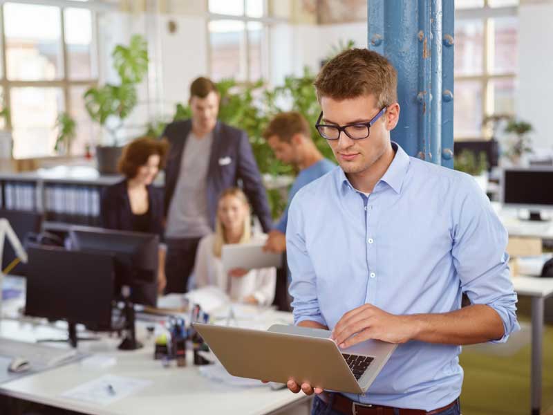 FollowMyMoney Geldanlage neu gedacht Business-Mann mit Laptop in der Hand in einem Büro