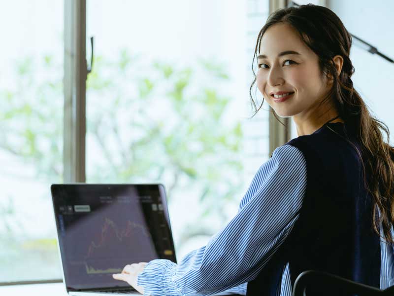 FollowMyMoney Kryptohandel - Business-Frau vor einem Laptop mit Aktiencharts
