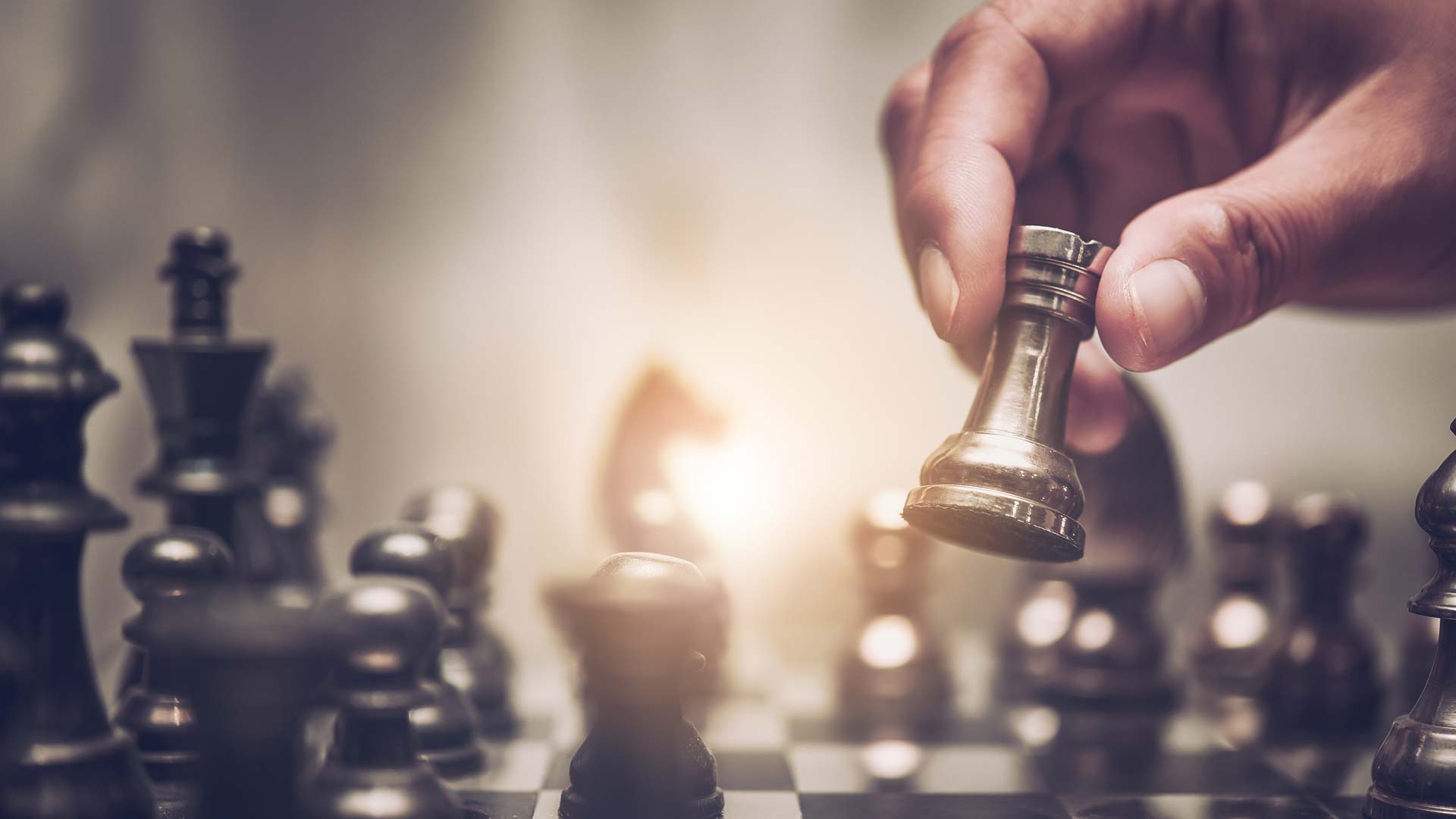 Schachbrett mit Figuren, Der weiße Turm ist in einer Hand im Vordergrund zu sehen